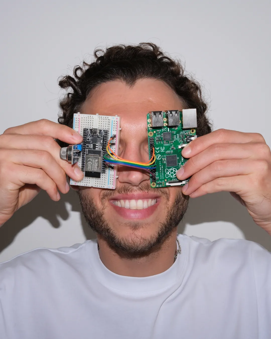 James Milton holding a breadboard and Raspberry Pi, with colourful wires stretched between them